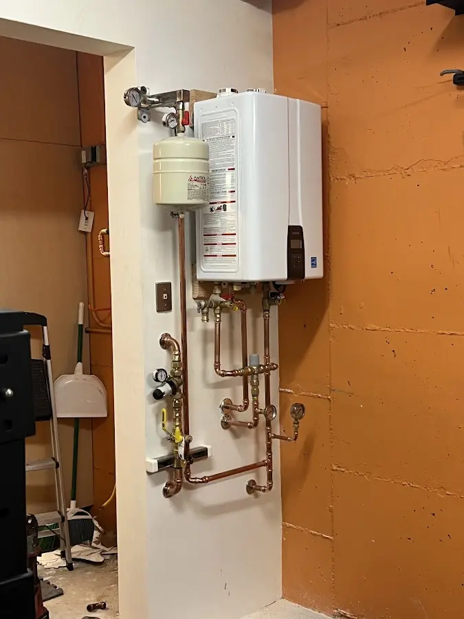 Plumbing technician inspecting water heater connections in Becker